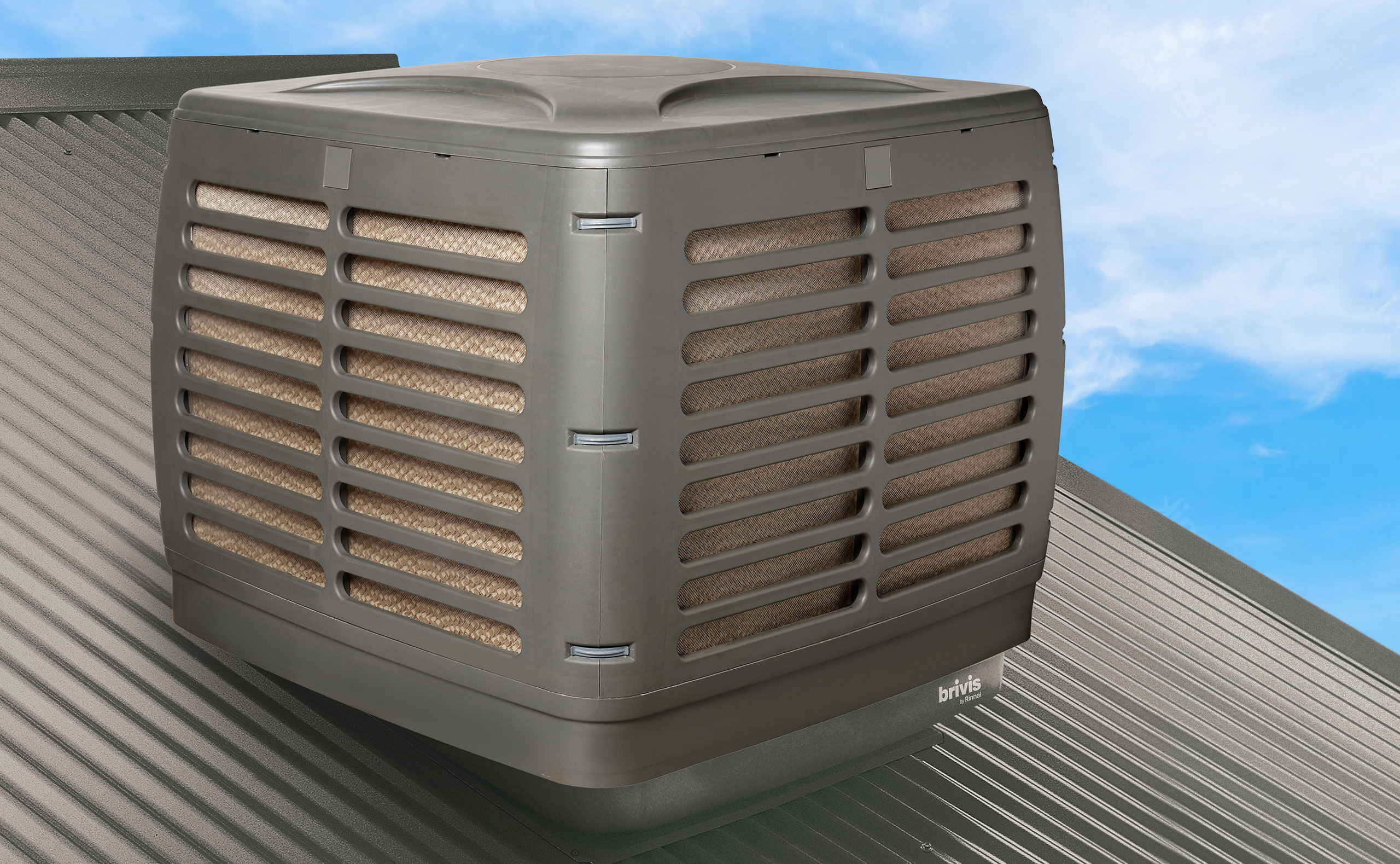 A modern Brivis evaporative air cooler unit with cooling pads visible, installed on a corrugated metal roof against a blue sky.