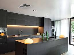 Modern kitchen with sleek black cabinetry and ducted split air conditioning system on ceiling for efficient cooling.